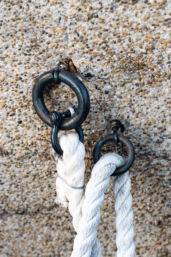 A vertical closeup shot of steel rings with white ropes