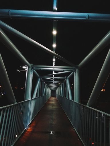 A vertical shot of the metal bridge at night during a rainy day