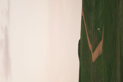 A vertical photo of a road through a lawn at sunset