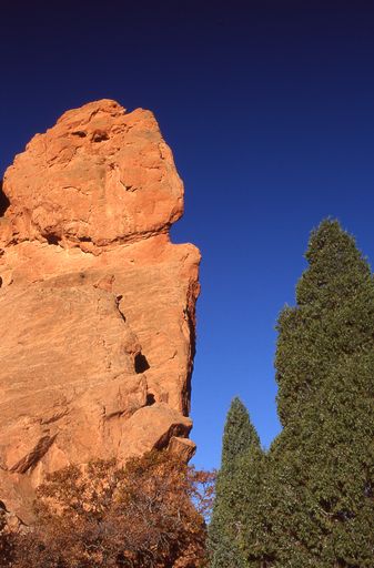 A vertical closeup shot of a big cliff formation with sunlights on it against a blue sky