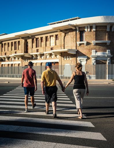 A vertical shot of three people crossing a street to a beautiful two-floor 
 old-fashioned building