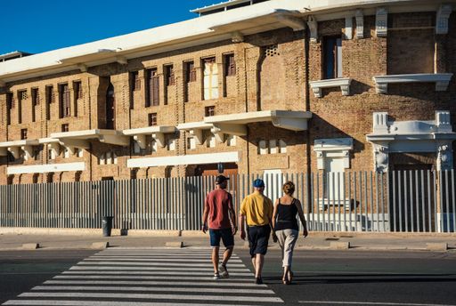 A horizontal shot of three people crossing a street to a beautiful two-floor 
 old-fashioned building