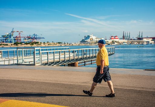 A horizontal bright view of a senior man walking in a city shore on a sunny day