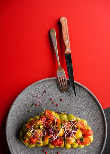 A vertical closeup of grilled bread with avocado puree and vegetables. Delicious meal.