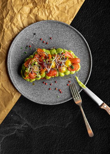 A vertical closeup of grilled bread with avocado puree and vegetables. Delicious meal.