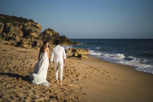 A caucasian loving couple wearing holding each other hands and walking in the beach during the wedding photoshop