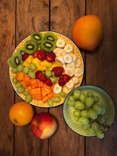A top view of fruit assortments on plates on a wooden table