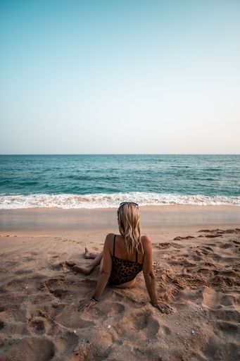 A vertical closeup shot of a female sitting at the coast of the ocean in Sri Lanka