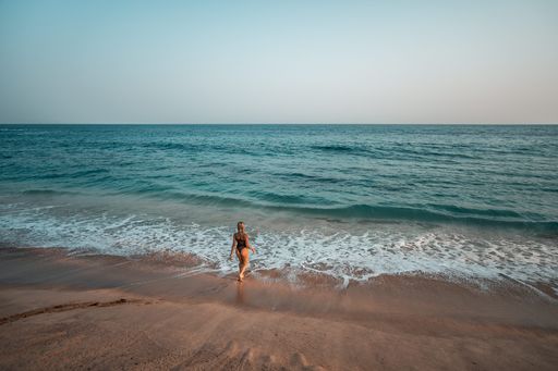 An aerial view of a young female walking towards the ocean during sunset in Sri Lanka
