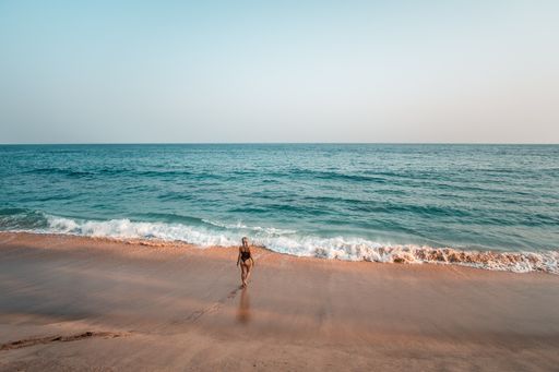 An aerial view of a young female walking towards the ocean during sunset in Sri Lanka
