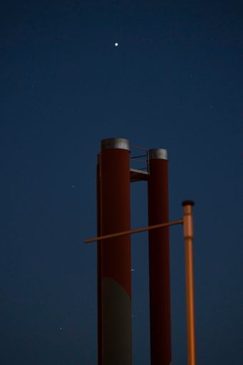 A vertical shot of an industrial tower against the blue sky in evening