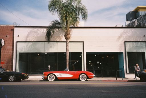 A red vintage car parked near a palm tree in LA