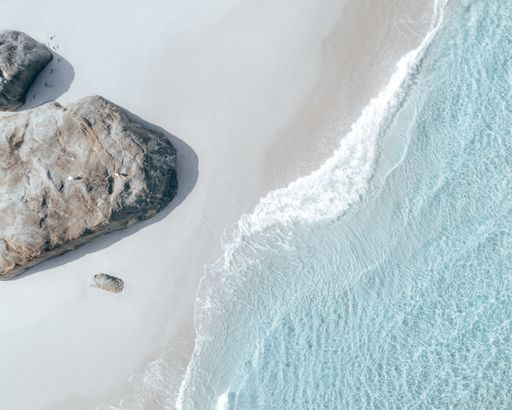A high angle top view shot of the sea waves brushing the sand in Western Australia DJI