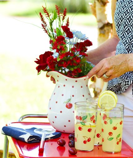 A vertical shot of flowers in a vase and a few refreshment drinks with lemon on a green yard background