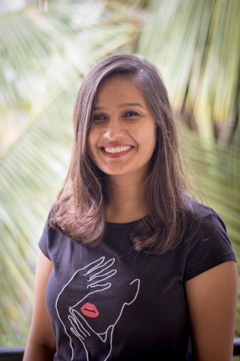 A vertical shot of a cute Indian woman smiling with her hair down while looking into the camera