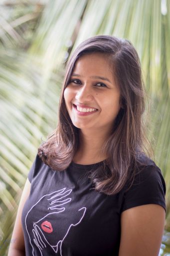 A vertical shot of a beautiful Indian woman smiling surrounded by lush greenery