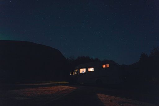 A horizontal shot of a white vehicle with lights under the beautiful starry sky at night time