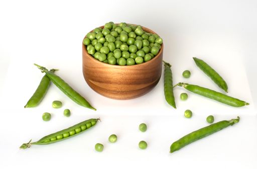 A bowl of green peas and some pods isolated on the white background
