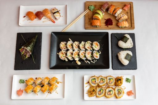 A top view of different kinds of sushi on plates on a white background