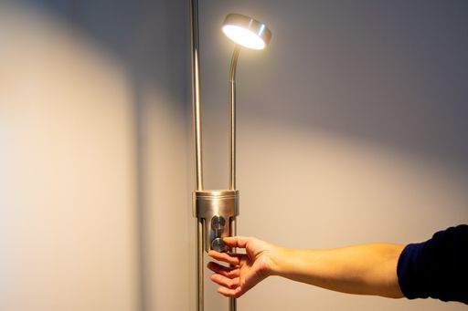 Hand of a woman turning on a lamp in a house with white background