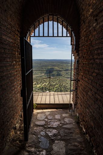 A vertical shot of a metal doorway leading to a dock with a view to a beautiful green field in Monfrague National Park, Spain