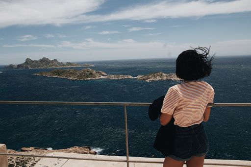 A beautiful shot of a short-haired female from her back standing on a dock and looking at a pure calm sea