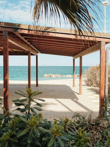 The area under wooden tend under palm on beautiful beach on a sunny day with vibrant colors in south Italy.