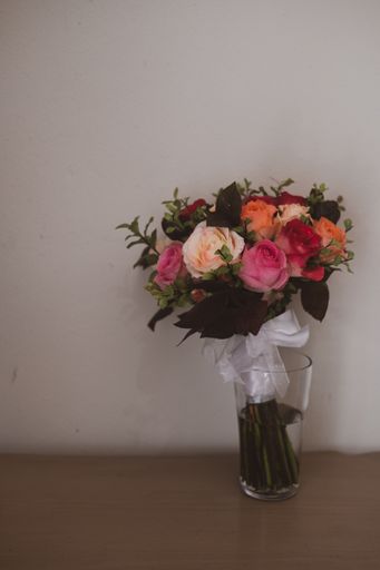 A vertical shot of a bouquet of colorful roses in a glass vase on a table