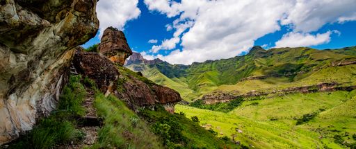 A scenic view of a green mountainous landscape in cloudy sky background