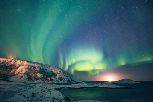A beautiful wide shot of aurora and the breathtaking starry sky with snowy hills and the lake