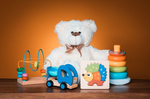 A closeup shot of colorful toys and a teddy bear isolated on the brown background