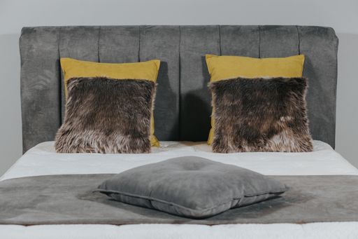 A closeup shot of a bed with gray fabric upholstery and stylish pillows