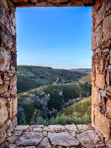 A natural view of mountain landscape under a clear sky seen from a stone-walled frame