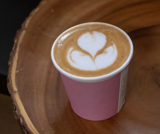 A selective focus shot of a cup of cappuccino with a tulip on the surface