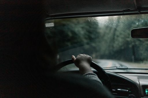 A girl drives her ford bronco truck through a Pacific Northwest West Coast Forest in the rain