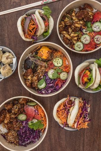 A top view shot of a table with Asian street food, poke bowl, bao, bun, chopsticks