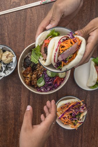 A top view shot of a table with Asian street food, poke bowl, bao, bun, chopsticks