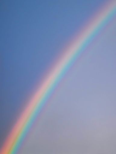 A vertical beautiful shot of rainbow on blue sky