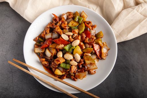 A closeup of oriental chicken with almonds traditional Chinese meal in a white plate
