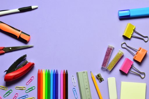 The assorted school supplies on a purple background
