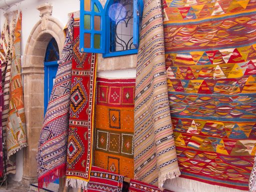A number of beautiful carpets with abstract decorations hanging on a wall in Essaouira, Morocco