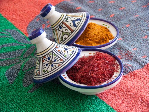 A closeup shot of Moroccan saffron and cumin in a traditional bowl on a colorful blanket