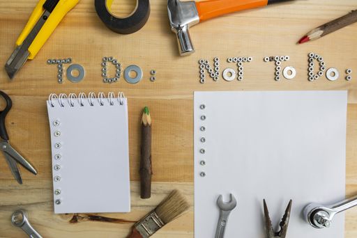 A high angle shot of the phrases "to do" and "not to do" made of screws and papers for each on a wooden surface for planning the work