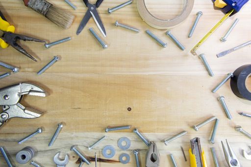A high angle shot of working instruments scattered on a wooden surface with space for text in the center
