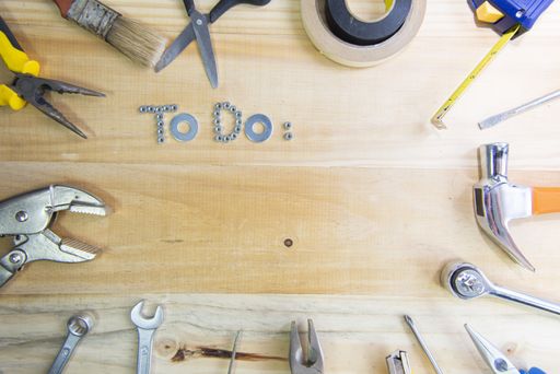 A high angle shot of the phrase "to do" made of screws surrounded by instruments on a wooden surface for planning the work