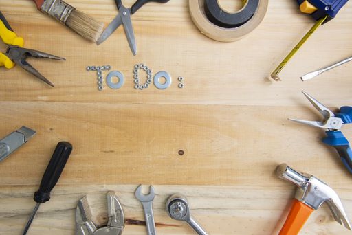 A high angle shot of the phrase "to do" made of screws surrounded by instruments on a wooden surface for planning the work