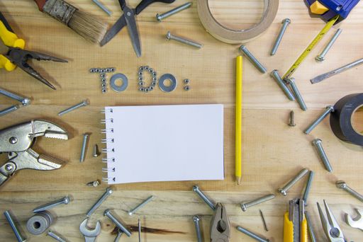 A high angle shot of the phrase "to do" made of screws and a blank notebook on a wooden surface for planning the work