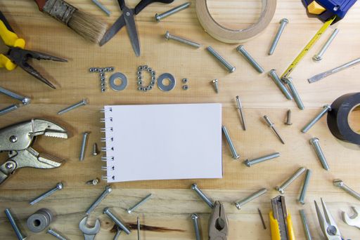 A high angle shot of the phrase "to do" made of screws and a blank notebook on a wooden surface for planning the work