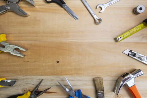 A high angle shot of working instruments scattered on a wooden surface with space for text in the center