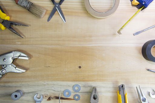 A high angle shot of working instruments scattered on a wooden surface with space for text in the center